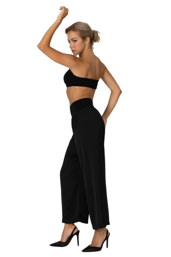 Woman wearing a black strapless top and wide-leg pants on a white background