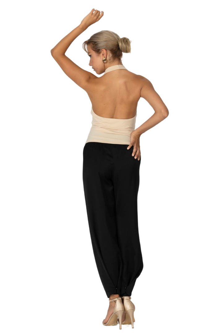 Woman wearing a beige top and black pants on a white background