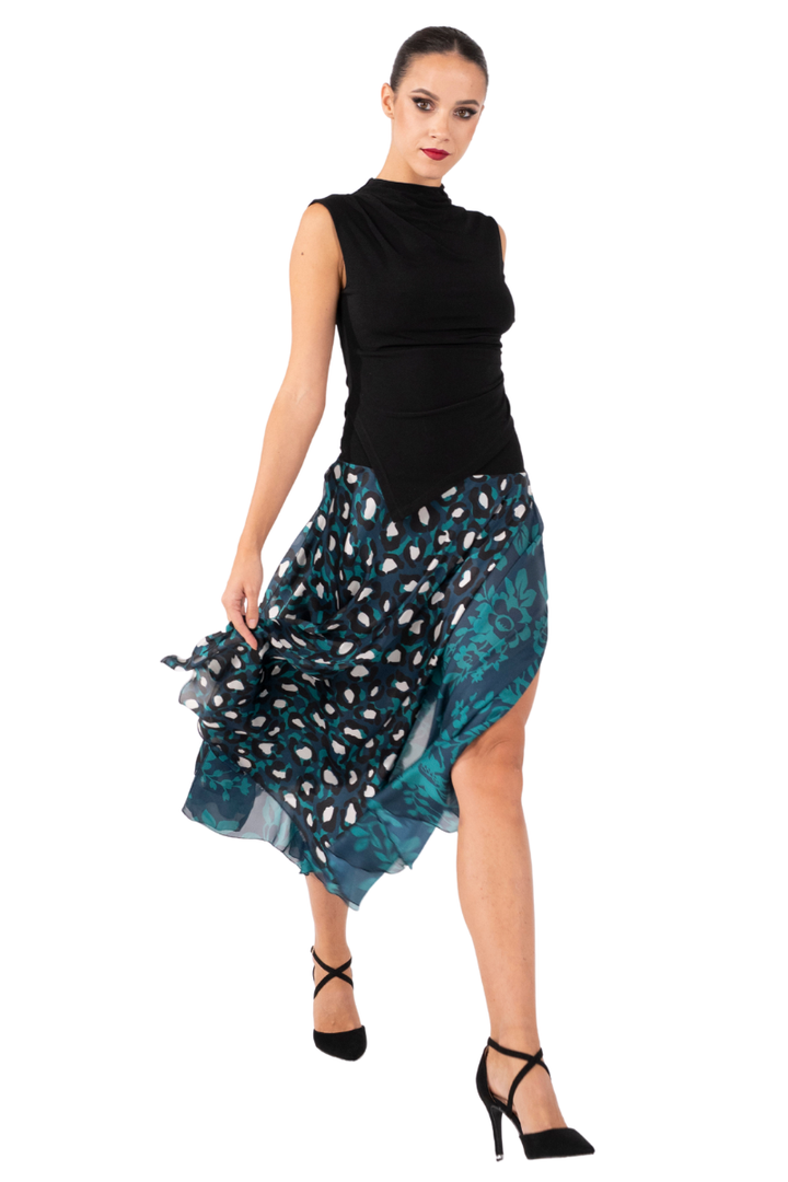 Woman wearing a black sleeveless top and a patterned teal skirt on a white background